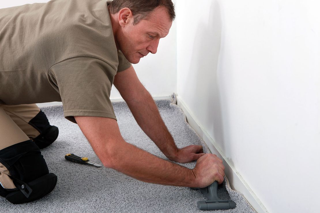 A professional carpet fitter, fitting a carpet